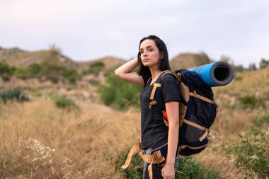 Genç dağcı kız dışarıda büyük bir sırt çantası taşıyor.