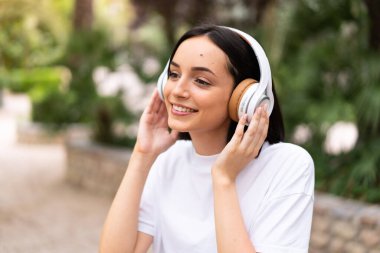 Açık havada müzik dinleyen genç bir kadın.