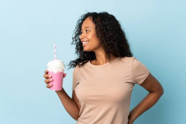 Çilekli milkshake 'li genç kız mavi arka planda izole edilmiş.