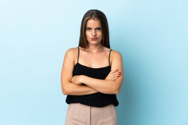 Genç Uruguaylı kadın mutsuz bir ifadeyle mavi arka planda izole edilmiş.