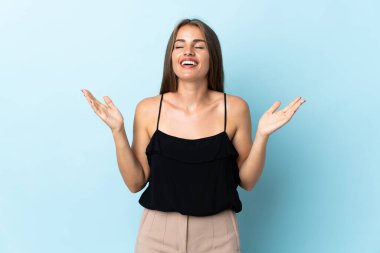 Genç Uruguaylı kadın mavi arka planda izole edilmiş, gülümsüyor.