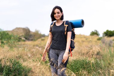 Genç dağcı kız dışarıda büyük bir sırt çantası taşıyor.