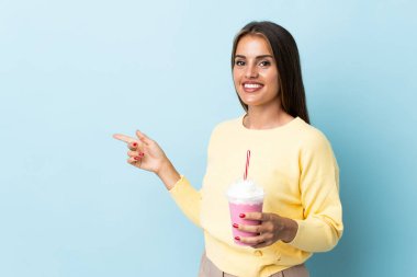 Çilekli milkshake 'li genç Uruguaylı kadın mavi arka planda izole edilmiş.