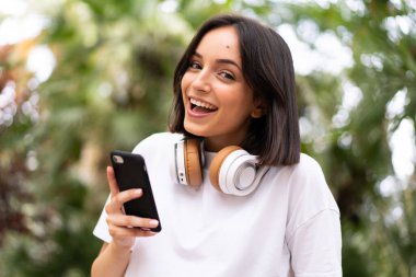 Açık havada telefon kullanan beyaz bir kadın.