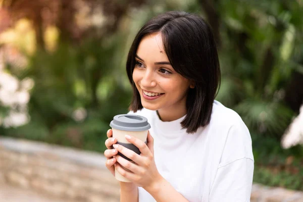 Young pretty woman holding coffee to take away at outdoors