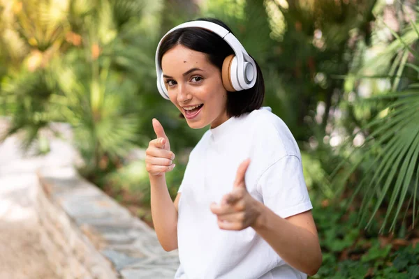 Mujer Joven Caucásica Con Auriculares Aire Libre Apuntando Frente Sonriendo — Foto de Stock