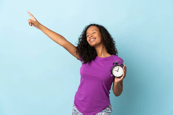Teenager Cuban Girl Isolated Blue Background Pajamas Holding Clock Happy — Stock Photo, Image