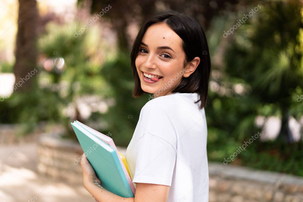 Young happy student woman holding notebooks at outdoors