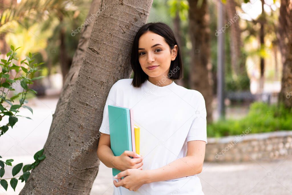Young caucasian student woman holding notebooks at outdoors