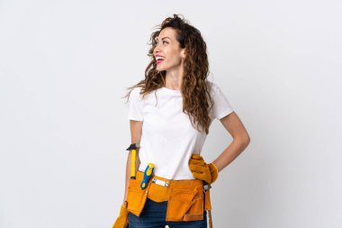 Beyaz arka planda izole edilmiş genç elektrikçi kolları kalçasında ve gülümsüyor.