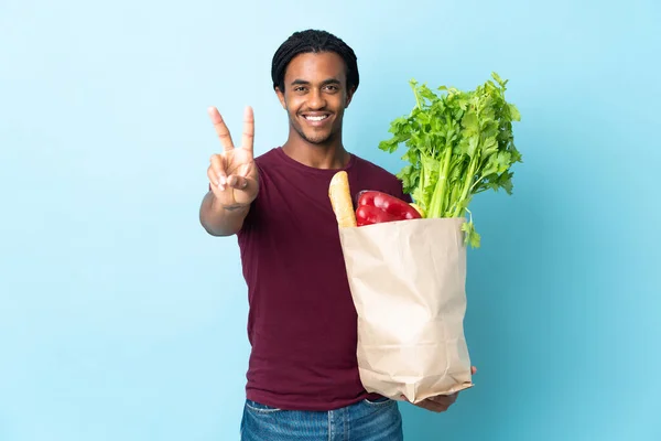 Uomo Afroamericano Possesso Sacchetto Della Spesa Isolato Sfondo Blu Sorridente — Foto Stock