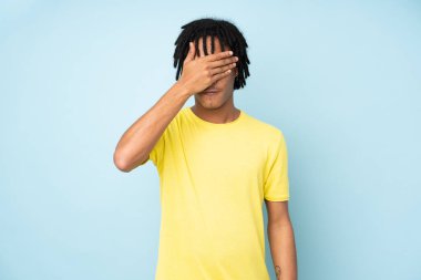 Genç Afro-Amerikalı bir adam mavi arka planda tek başına, gözleri elleriyle kapatıyor. Bir şey görmek istemiyorum.