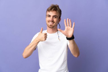 Mor arka planda izole edilmiş yakışıklı sarışın adam parmakları olan altı kişi sayıyor.