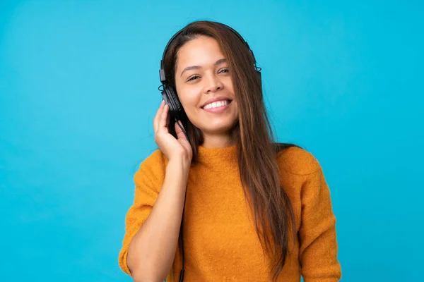 Mujer Joven Escuchando Música Sobre Una Pared Azul Aislada —  Fotos de Stock