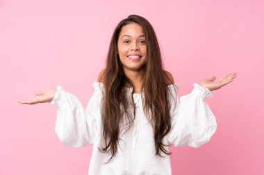 İzole edilmiş pembe arka planı olan Brezilyalı genç kız çok gülümsüyor.