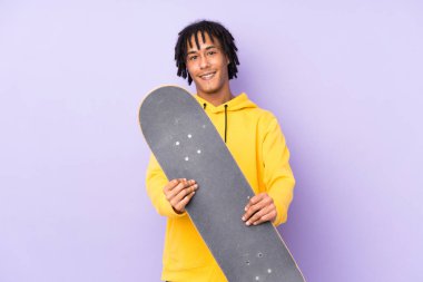 Yakışıklı genç kaykaycı mutlu bir ifadeyle izole duvarın üzerinde.