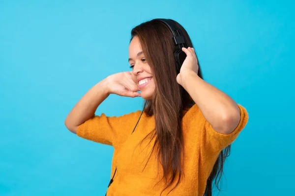 Mujer Joven Escuchando Música Sobre Una Pared Azul Aislada —  Fotos de Stock
