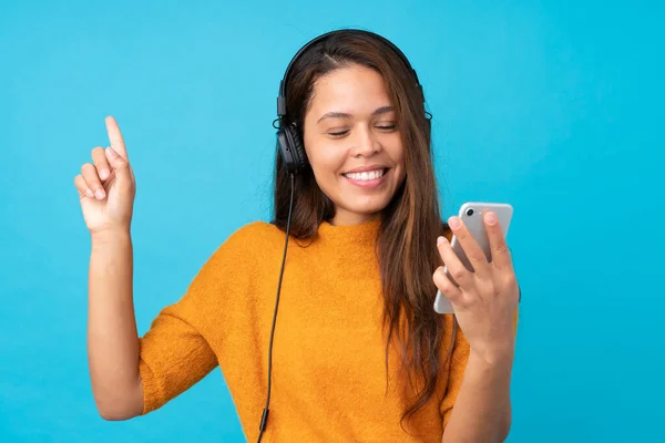 Mujer Joven Escuchando Música Con Móvil Sobre Una Pared Azul —  Fotos de Stock