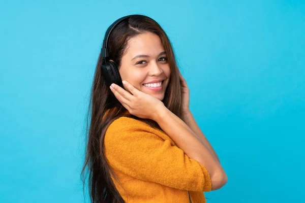 Mujer Joven Escuchando Música Sobre Una Pared Azul Aislada —  Fotos de Stock