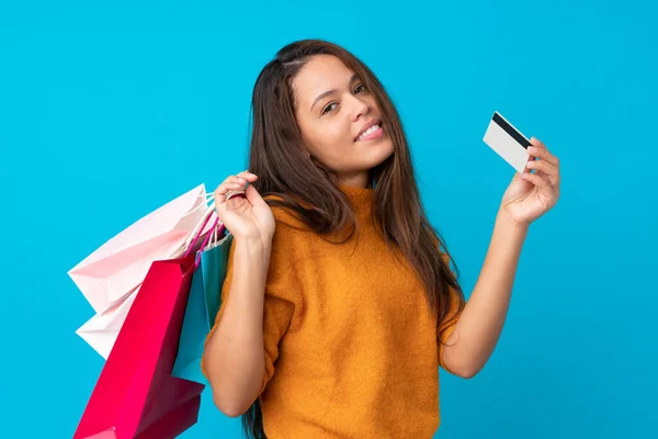 Ung Brasiliansk Flicka Över Isolerad Blå Bakgrund Håller Shoppingväskor Och — Stockfoto