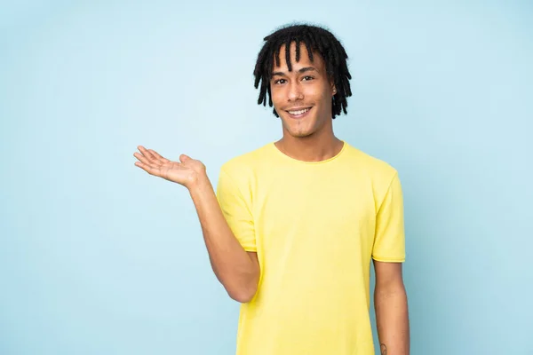 ヤシの上に想像上のコピースペースを保持青い背景に隔離された若いアフリカ系アメリカ人男性が広告を挿入する — ストック写真
