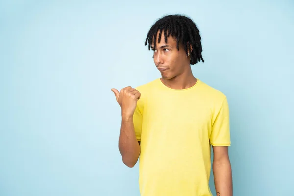 Jovem Afro Americano Isolado Fundo Azul Infeliz Apontando Para Lado — Fotografia de Stock