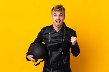 Sarı arka planda izole edilmiş motosiklet kasklı bir adam galibiyeti kutluyor.