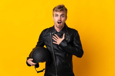 Sarı arka planda izole edilmiş motosiklet kasklı bir adam sağa bakarken şaşırmış ve şok olmuştu.