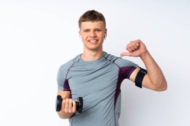 Halter kaldıran genç sporcu kendini beğenmiş ve gururlu beyaz duvar üzerinde