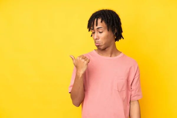 Jovem Afro Americano Isolado Fundo Amarelo Infeliz Apontando Para Lado — Fotografia de Stock