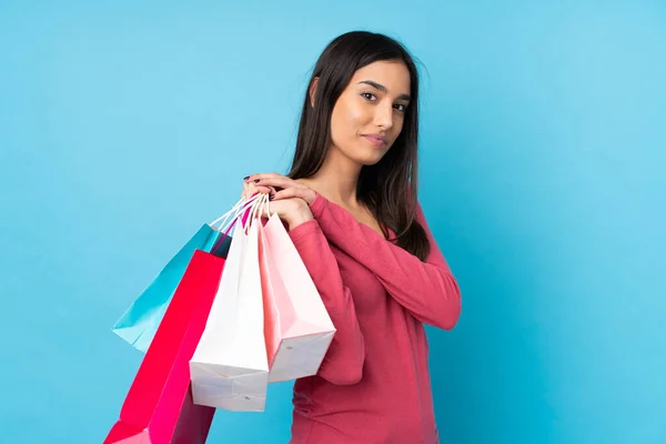 Junge Brünette Frau Über Isoliertem Blauem Hintergrund Mit Einkaufstaschen — Stockfoto