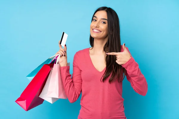 Jonge Brunette Vrouw Geïsoleerde Blauwe Achtergrond Met Winkeltassen Een Creditcard — Stockfoto