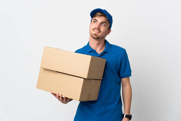 Young delivery blonde man isolated on white background thinking an idea while looking up