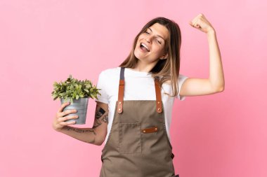 Bahçıvan kadın pembe arka planda bir bitki tutuyor zaferi kutluyor.