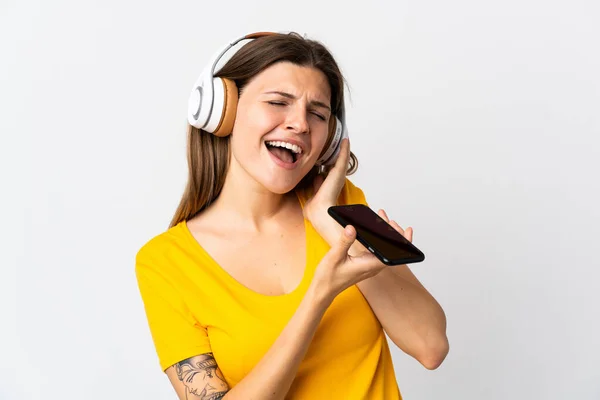 Νεαρή Γυναίκα Απομονωμένη Λευκό Φόντο Ακούγοντας Μουσική Κινητό Και Τραγουδώντας — Φωτογραφία Αρχείου