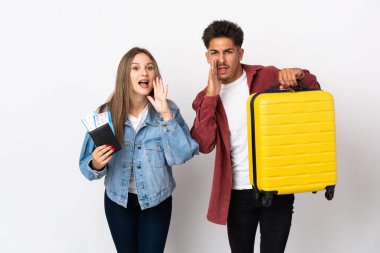 Mavi arka planda izole edilmiş bir bavul taşıyan gezgin çift bağırıyor ve bir şey duyuruyor.