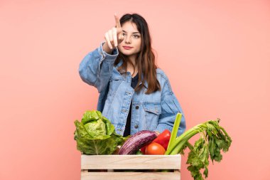 Genç çiftçi kadın elinde bir sepet dolusu taze sebzeyle şeffaf ekrana dokunuyor.