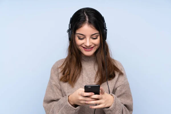 Jeune Femme Brune Sur Fond Bleu Isolé Écoutant Musique Regardant — Photo