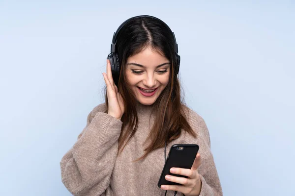 Joven Morena Sobre Fondo Azul Aislado Escuchando Música Con Móvil —  Fotos de Stock