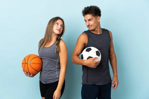 Jovem Casal Jogando Futebol Basquete Isolado Fundo Azul Olhando Sobre — Fotografia de Stock