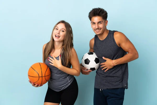 Jovem Casal Jogando Futebol Basquete Isolado Fundo Azul Sorrindo Muito — Fotografia de Stock