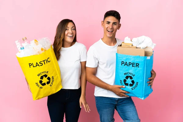 Casal Jovem Segurando Saco Cheio Plástico Papel Isolado Fundo Rosa — Fotografia de Stock