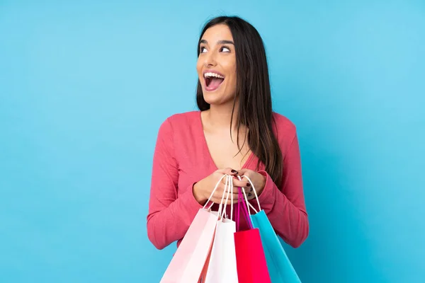 Jonge Brunette Vrouw Geïsoleerde Blauwe Achtergrond Holding Shopping Tassen Verrast — Stockfoto