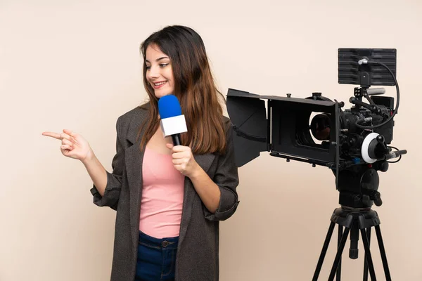Reporter woman holding a microphone and reporting news over isolated background extending hands to the side for inviting to come