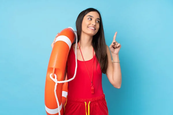 Lifeguard woman over isolated blue background with lifeguard equipment and intending to realizes the solution