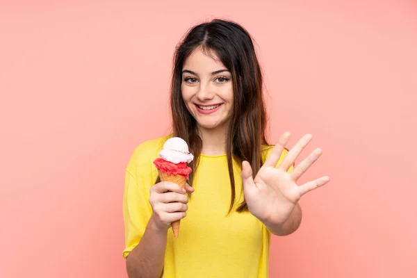 Joven Morena Sosteniendo Helado Corneta Sobre Fondo Rosa Aislado Saludando —  Fotos de Stock