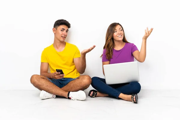 Casal Jovem Com Laptop Sentado Chão Isolado Fundo Branco Estendendo — Fotografia de Stock