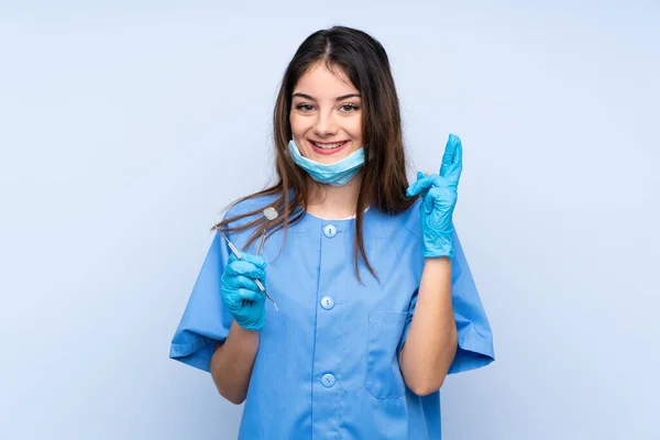 Žena Zubař Drží Nástroje Přes Izolované Modré Pozadí Prsty Kříž — Stock fotografie