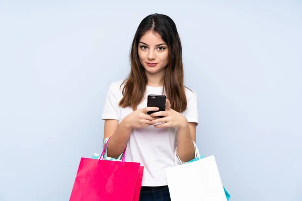 Jovem Morena Sobre Fundo Azul Isolado Segurando Sacos Compras Escrevendo — Fotografia de Stock