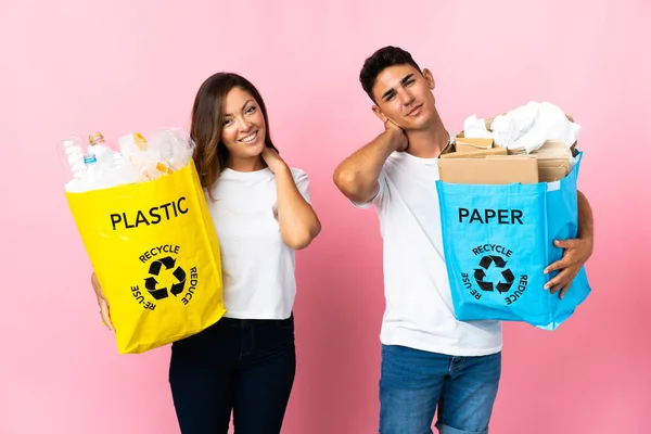 Casal Jovem Segurando Saco Cheio Plástico Papel Isolado Fundo Rosa — Fotografia de Stock